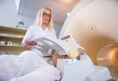 Radyolog genç bayanı MRI beyin muayenesine hazırlıyor.