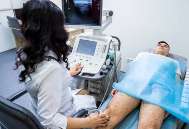 Doktor, yaralı dizleri inceleyen ultrason tarama makinesi kullanıyor.