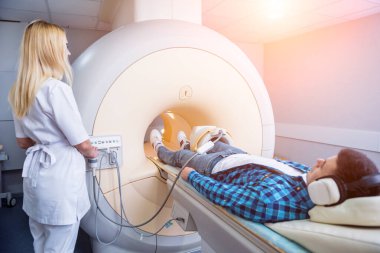 Radyoloji uzmanı hastayı MRI diz muayenesi için hazırlıyor.