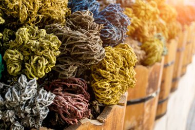 Dekoratif toplara dönüşmüş renkli kurumuş deniz yosunu sokak pazarındaki ahşap sepetlerde yatıyor.