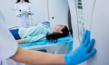 Radyolog, bilgisayarlı tomografi odasında bir kadın hasta ile birlikte.