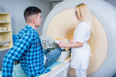 Radyoloji uzmanı hastayı MRI diz muayenesi için hazırlıyor.