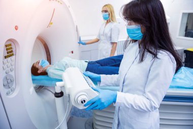 Radyolog, bilgisayarlı tomografi odasında bir kadın hasta ile birlikte.