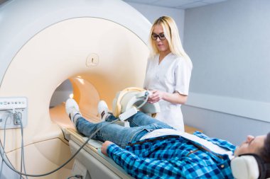 Radyoloji uzmanı hastayı MRI diz muayenesi için hazırlıyor.