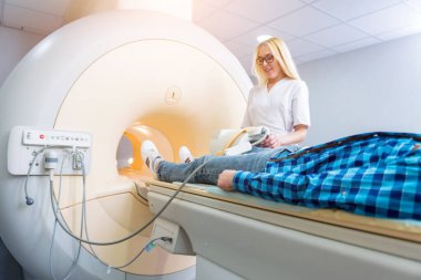 Radyoloji uzmanı hastayı MRI diz muayenesi için hazırlıyor.