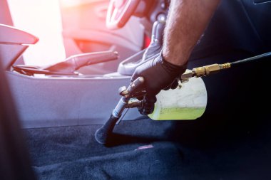 Bir araba servisi çalışanı özel köpük jeneratörüyle iç mekanı temizler.