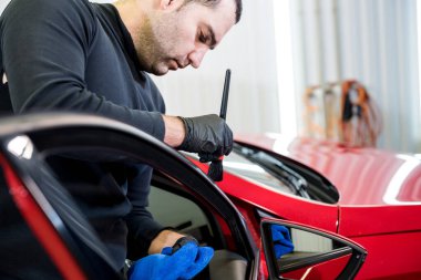 Araba servisi çalışanı iç mekanı özel fırçayla temizliyor