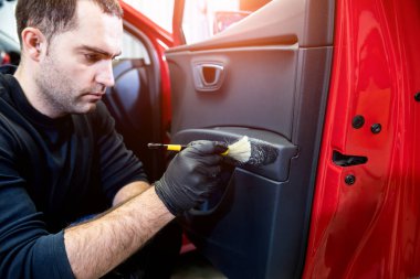 Araba servisi çalışanı iç mekanı özel fırçayla temizliyor