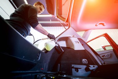 Bir araba servisi çalışanı özel köpük jeneratörüyle iç mekanı temizler.