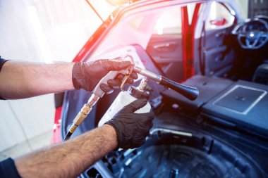 Bir araba servisi çalışanı özel köpük jeneratörüyle iç mekanı temizler.