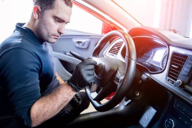 Bir araba servisi çalışanı araba konsolunu özel bir fırçayla temizler.