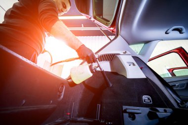 Bir araba servisi çalışanı özel köpük jeneratörüyle iç mekanı temizler.