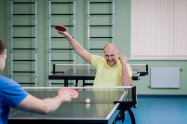 Tekerlekli sandalyede masa tenisi oynayan yetişkin erkekler