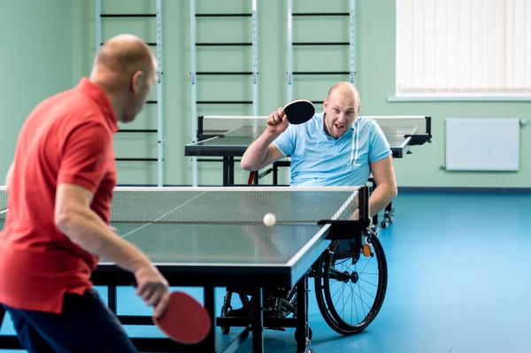 Adult disabled man in a wheelchair play at table tennis with his coach — Stock Photo, Image