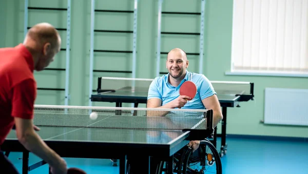 Behinderter Mann im Rollstuhl spielt mit seinem Trainer Tischtennis — Stockfoto