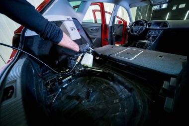 Bir araba servisi çalışanı özel köpük jeneratörüyle iç mekanı temizler.