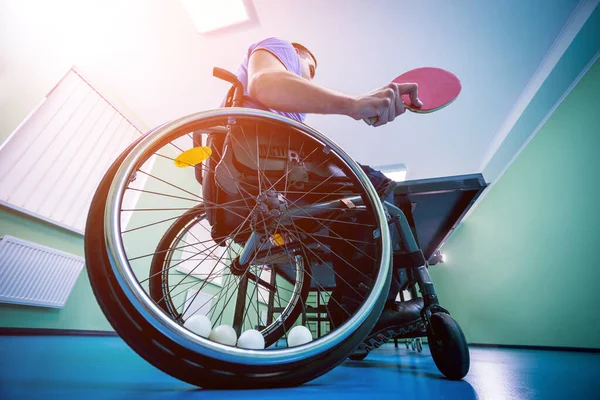 Инвалид в инвалидной коляске играет в настольный теннис. теннисные мячи, зафиксированные в колесе — стоковое фото