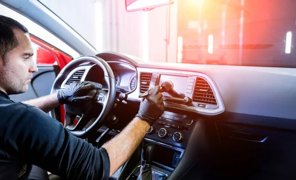 Een autobediener reinigt de autoconsole met een speciale borstel — Stockfoto