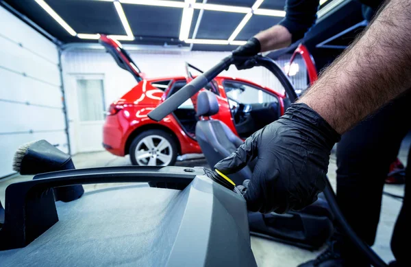 Auto service werknemer schoonmaken autostoel met stofzuiger. — Stockfoto