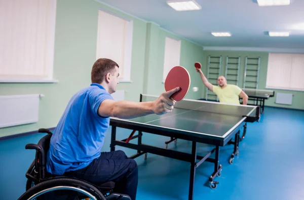 Взрослые инвалиды в инвалидной коляске играют в настольный теннис — стоковое фото