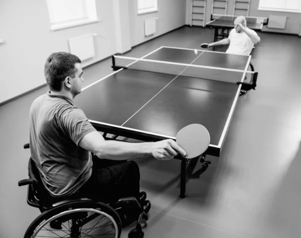 Dorośli niepełnosprawni mężczyźni na wózku inwalidzkim grający w tenisa stołowego — Zdjęcie stockowe
