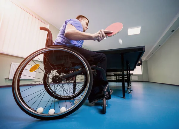 Un handicapé en fauteuil roulant joue au tennis de table. Balles de tennis fixées dans une roue — Photo