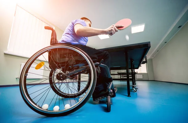 Un hombre discapacitado en silla de ruedas juega al ping-pong. Pelotas de tenis fijadas en una rueda —  Fotos de Stock