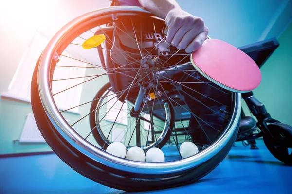 Un hombre discapacitado en silla de ruedas juega al ping-pong. Pelotas de tenis fijadas en una rueda —  Fotos de Stock