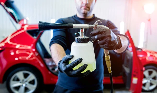 Ein Autoservice-Mitarbeiter reinigt den Innenraum mit einem speziellen Schaumgenerator — Stockfoto