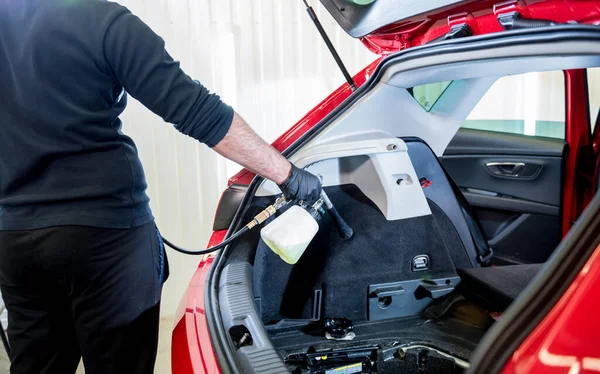 Egy autószerelő egy speciális habgenerátorral tisztítja meg a belső teret. — Stock Fotó