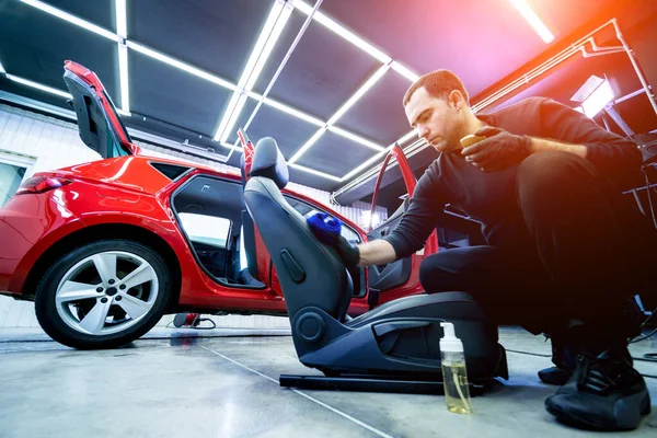 Trabajador de servicio de coche limpia una silla de coche con un paño de microfibra especial — Foto de Stock