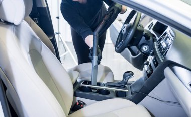 İşçi arabanın içini elektrikli süpürgeyle temizliyor