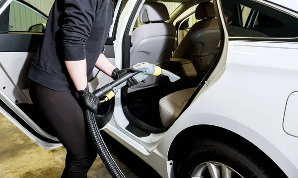 Worker cleans car interior with vacuum cleaner