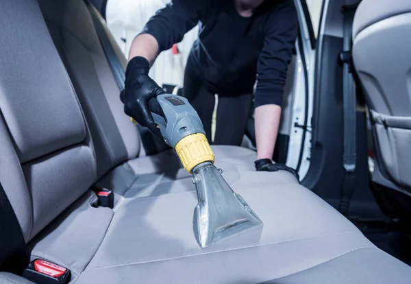 Arbetaren rengör bilens inredning med dammsugare — Stockfoto