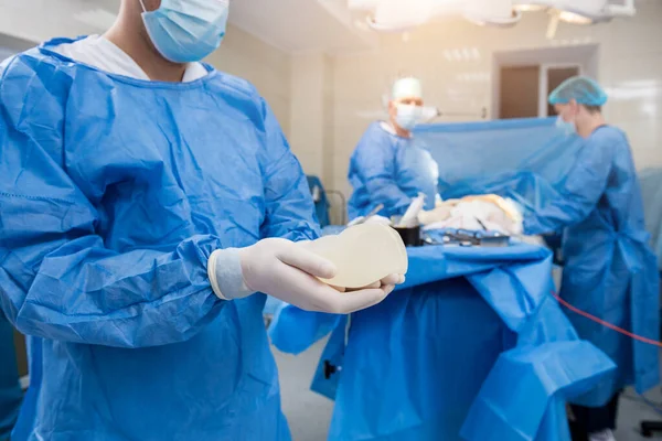 Cirujano en quirófano sostiene implante de silicona estéril en las manos. —  Fotos de Stock