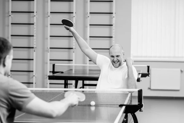 Дорослі чоловіки з обмеженими можливостями в інвалідному візку грають в настільний теніс — стокове фото