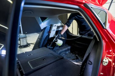 Bir araba servisi çalışanı özel köpük jeneratörüyle iç mekanı temizler.