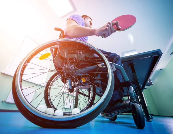 Un hombre discapacitado en silla de ruedas juega al ping-pong. Pelotas de tenis fijadas en una rueda — Foto de Stock