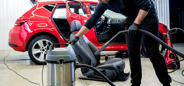 Bilservicearbetare städar bilbarnstol med dammsugare. — Stockfoto