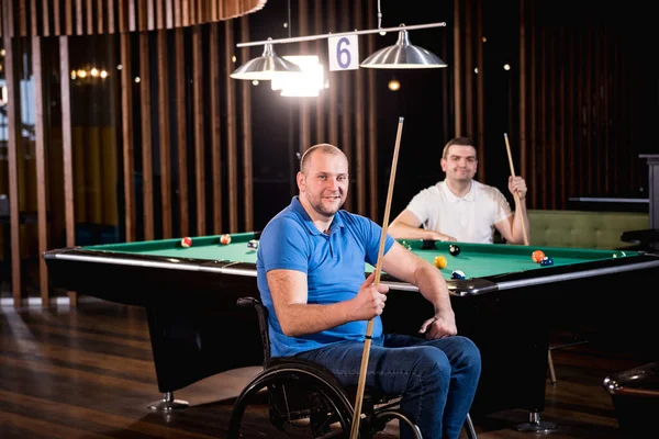 Дорослі чоловіки з обмеженими можливостями в інвалідному візку грають в більярд в клубі — стокове фото