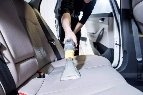 Werknemer reinigt auto interieur met stofzuiger — Stockfoto