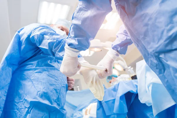 Asistente ayuda al cirujano a ponerse guantes de látex y bata quirúrgica antes de la operación. — Foto de Stock