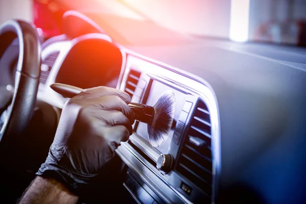 Een autobediener reinigt de autoconsole met een speciale borstel — Stockfoto