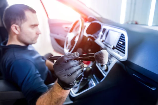 En bilservicearbetare rengör bilkonsolen med en speciell borste — Stockfoto