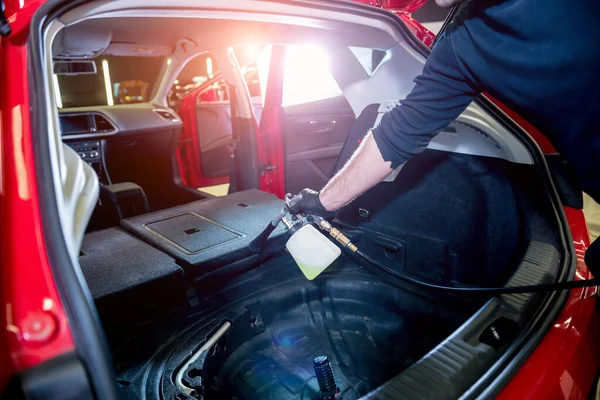 Bir araba servisi çalışanı özel köpük jeneratörüyle iç mekanı temizler.