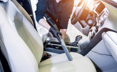 İşçi arabanın içini elektrikli süpürgeyle temizliyor