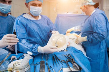 Ameliyathanedeki cerrah steril göğüs silikonu elinde tutuyor..