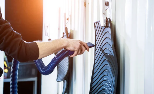 Man drying car carpet with vacuum cleaner after washing