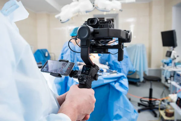 El videógrafo dispara al cirujano y a los asistentes en el quirófano con equipo quirúrgico — Foto de Stock