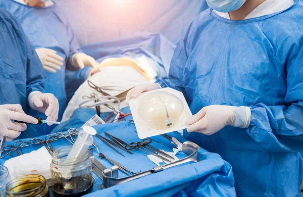 Chirurg im Operationssaal hält steriles Silikonimplantat in der Hand. — Stockfoto